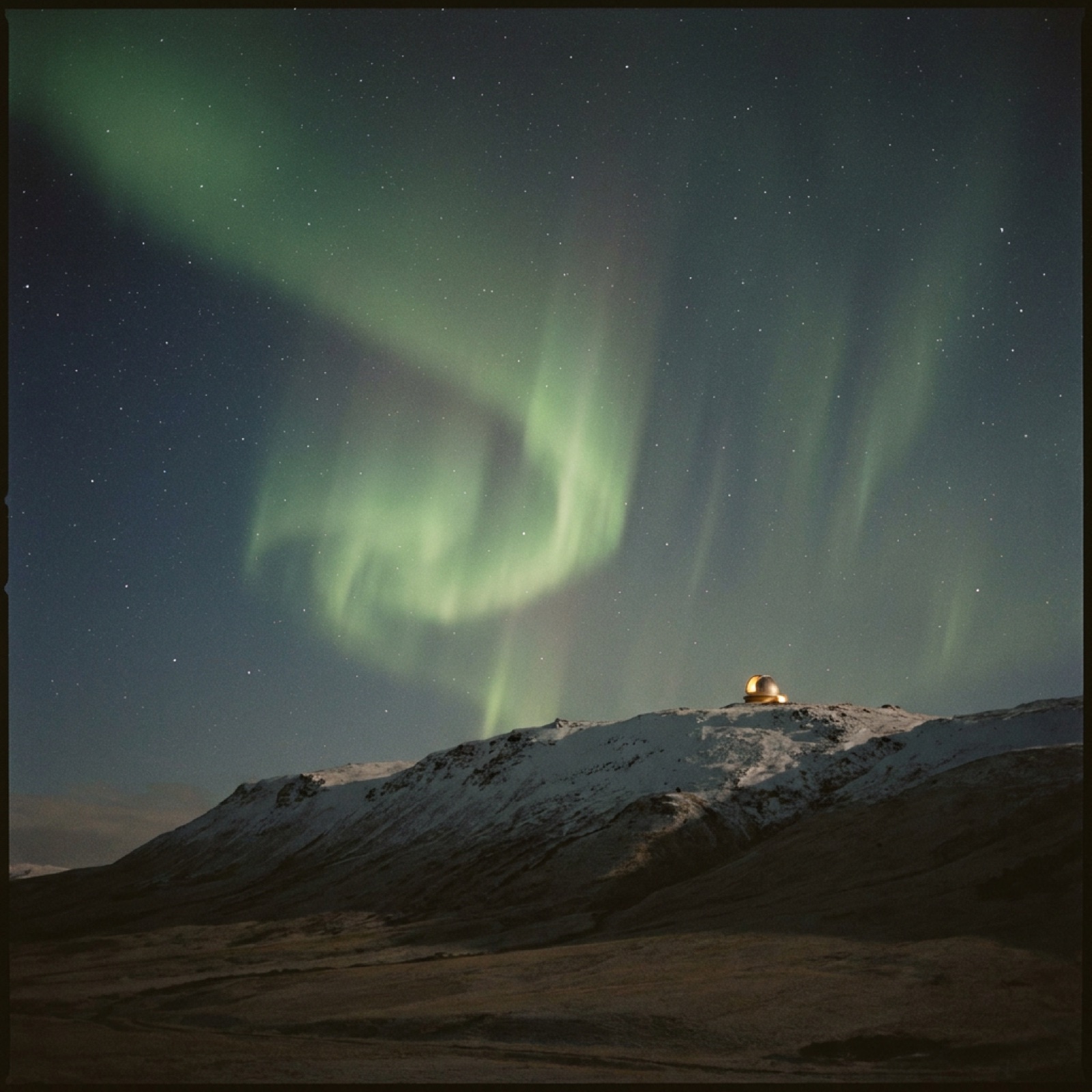 A green aurora arcing over the dark alpine ridge