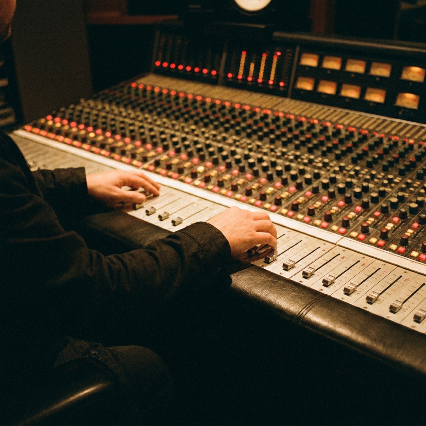 A mixing console in a darkened studio, meters glowing