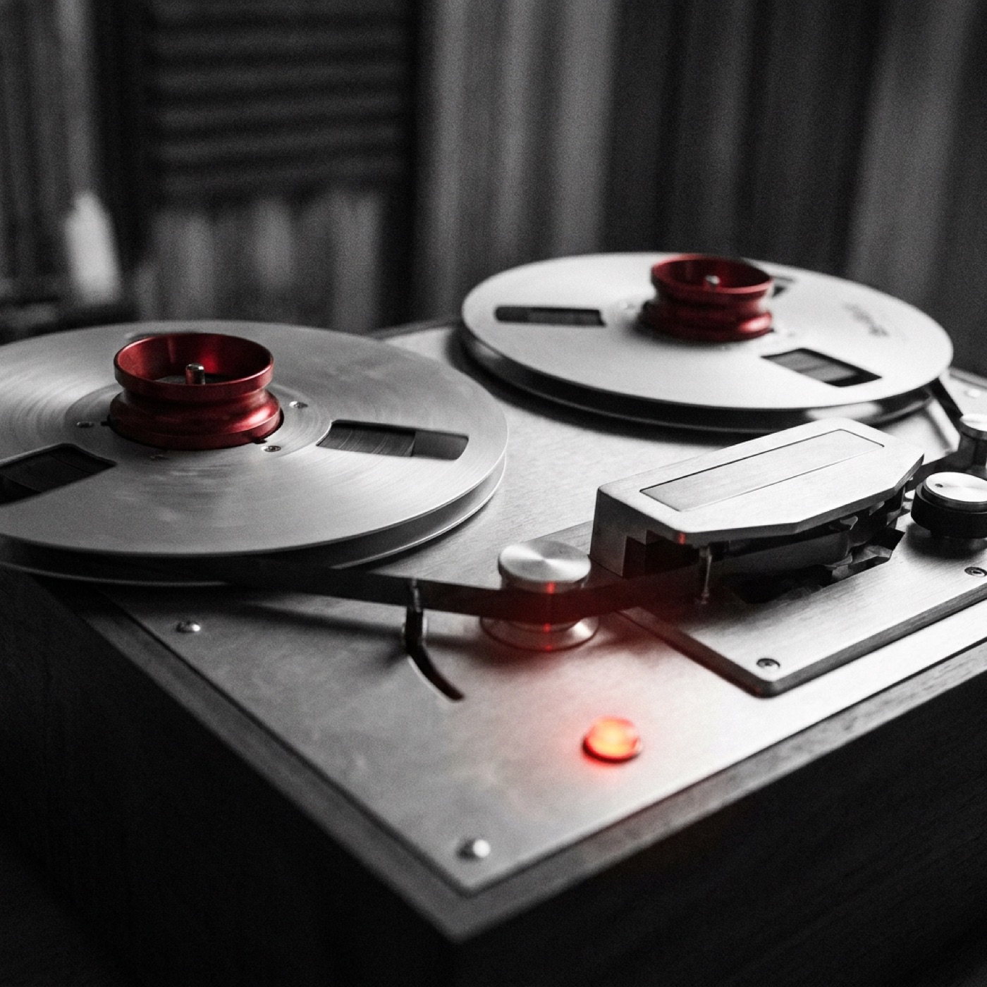 A reel-to-reel tape machine mid-spool in black and white